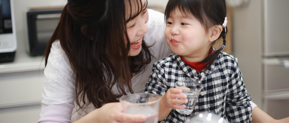 mother and daughter holding a glass of drinking water