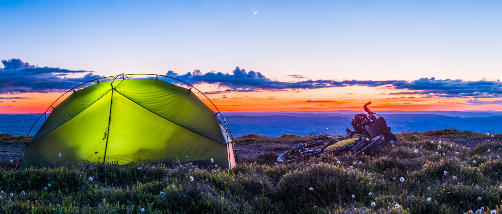 night time backpacking scene tent and bike with sunset