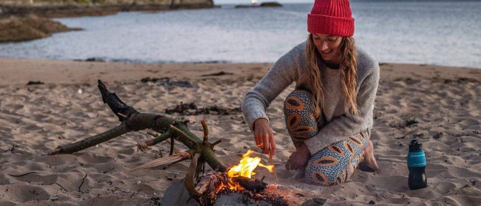 Woman at campfire on beach with Water to Go Classic water filter bottle
